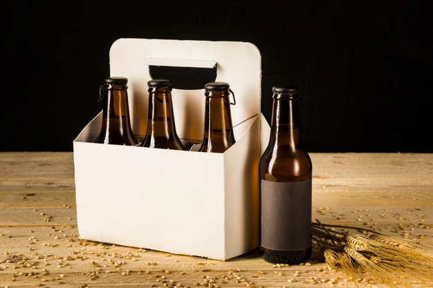 caixa-de-embalagem-de-garrafa-de-cerveja-e-espigas-de-trigo-na-superficie-de-madeira_23-2147952060